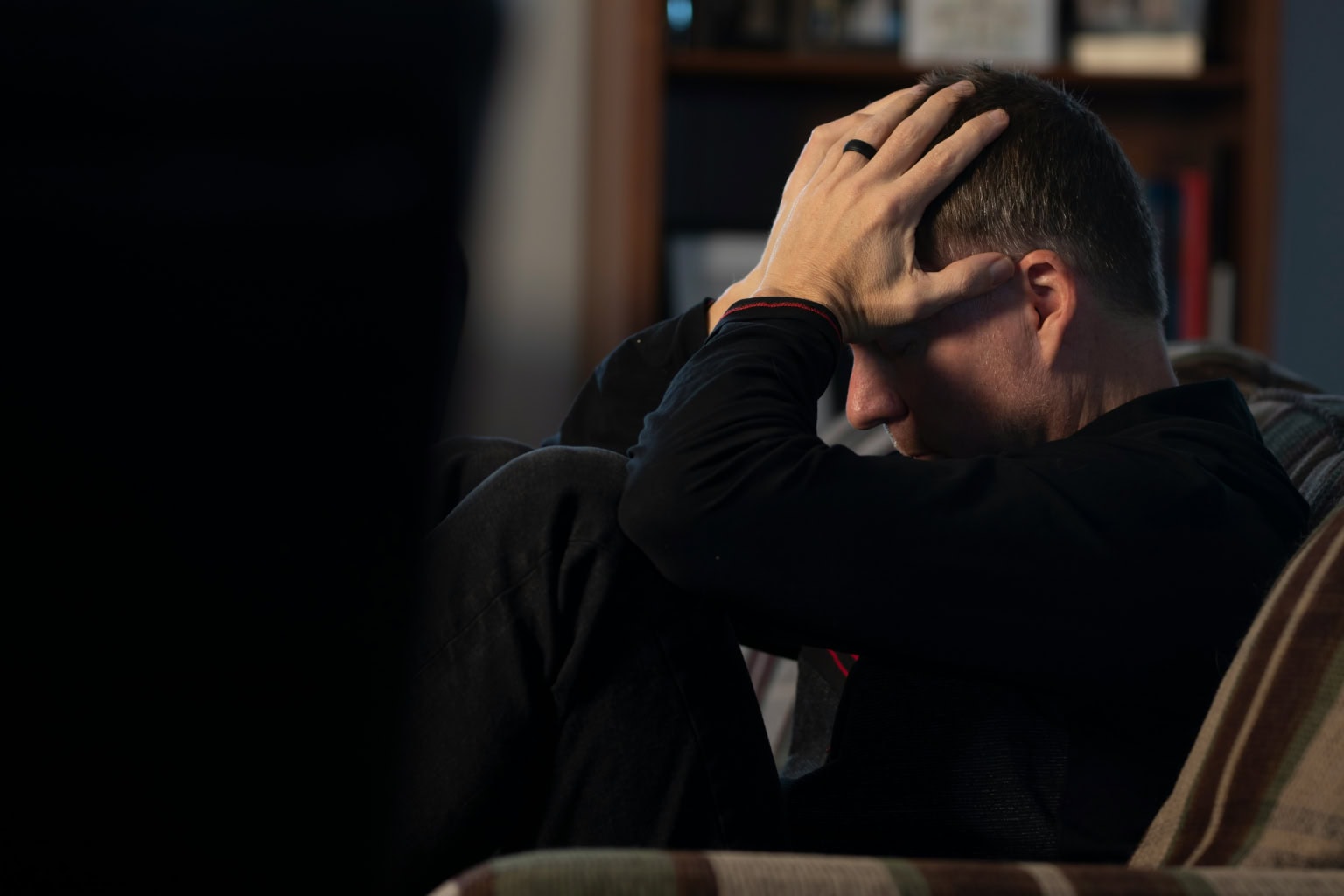Man met mentale stress houdt hoofd vast in een rustige kamer.